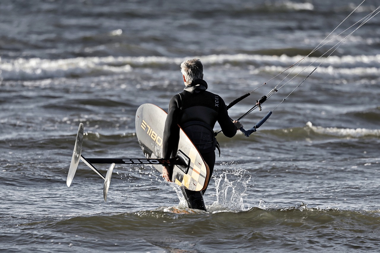 Rider carrying a hydrofoil board out into shallow water