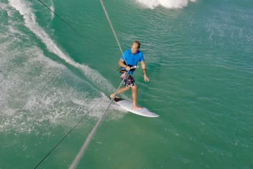 Kiteboarder riding a strapless surfboard down the face of a wave