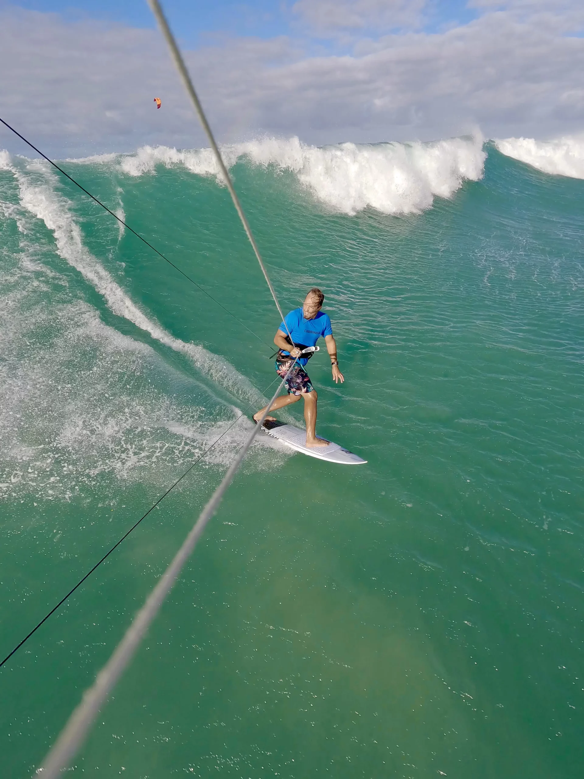 Kiteboarder riding a strapless surfboard down the face of a wave